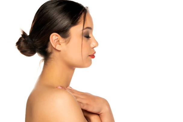 profil egy gyönyörű fiatal nő gyengéden megérinti a nyakát ellen fehér háttér - Fotó, kép