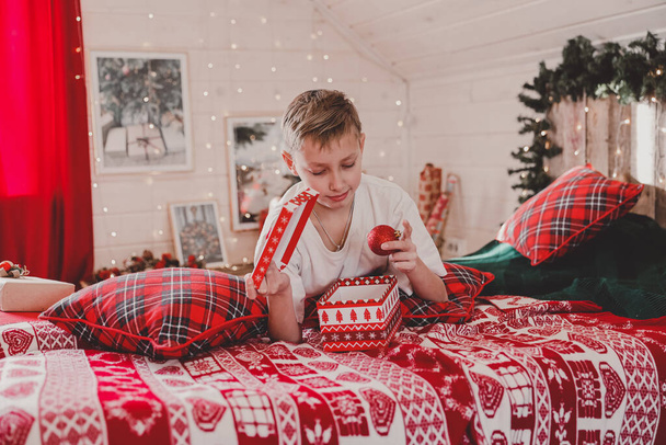 Child boy decorating Christmas tree at home. Family with kids celebrate winter holidays. Kids decorate living room and fireplace for Christmas. Bedroom new year decor - Foto, Imagen