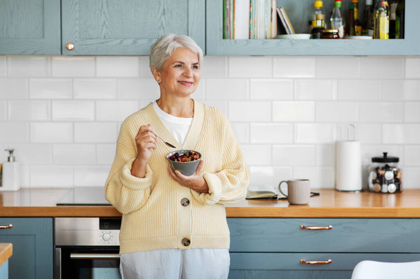 woman with cereal for breakfast on kitchen at home - Foto, afbeelding