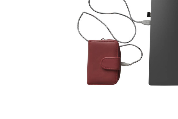 Laptop, oplader en rode portemonnee op een witte achtergrond. Het concept om thuis geld te verdienen. Uitzicht van bovenaf. - Foto, afbeelding