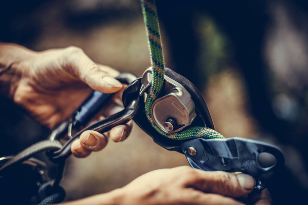 Close up shot of a man's hands operating a rock climbing assisted belaying device. - Foto, Imagem
