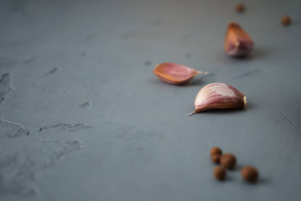Garlic cloves and black pepper peas on a concrete surface. Copy space - Fotografie, Obrázek