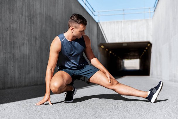 man doing sports and stretching leg outdoors - Foto, immagini