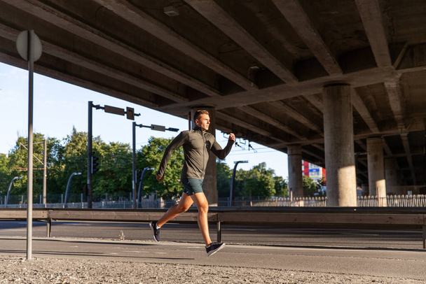 young man running outdoors under bridge - Foto, Imagen
