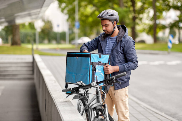 man with food delivery bag and bicycle in city - Foto, afbeelding