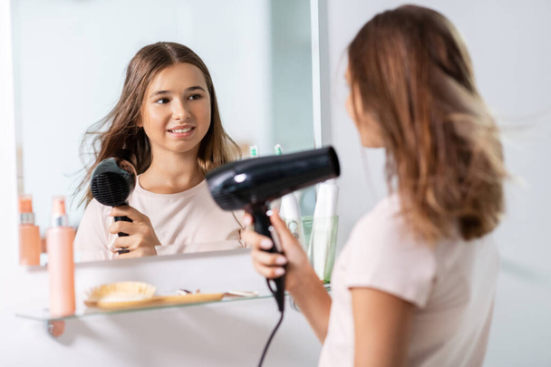 teenage girl with hair dryer at bathroom - Foto, immagini