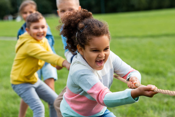 happy children playing tug-of-war game at park - Photo, image