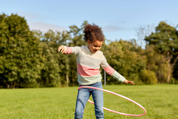 happy girl playing with hula hoop at park - Фото, изображение