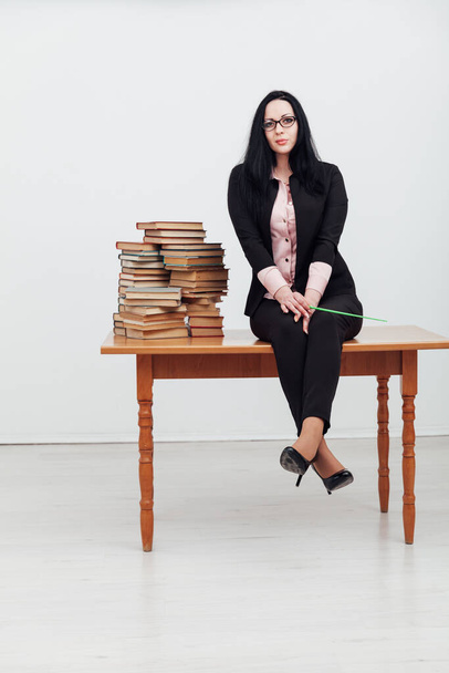 жінка брюнетка в бізнес-костюмі вчитель зі стосами книг
 - Фото, зображення