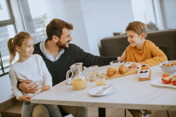 Młody ojciec je śniadanie z synem i córką w domu - Zdjęcie, obraz