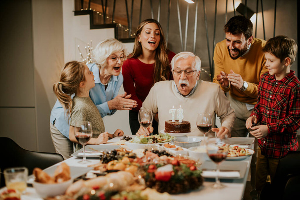 Mutlu aile büyükbabanın doğum gününü evde pasta ve mumlarla kutluyor. - Fotoğraf, Görsel
