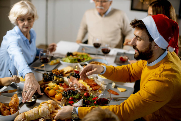 Feliz familia multigeneracional celebrando el Año Nuevo junto a la mesa en casa - Foto, imagen