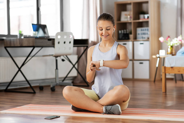 teenage girl with gadgets exercising at home - 写真・画像