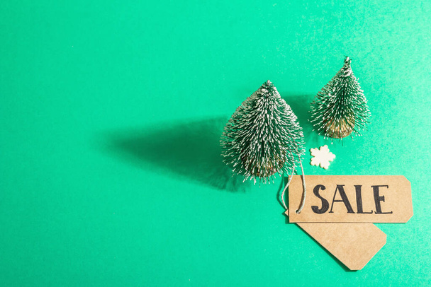 Christmas Sale concept on turquoise background. Decorative fir tree and paper tag.Traditional New Year symbol. A trendy hard light, dark shadow. Flat lay, mockup, template, top view - 写真・画像
