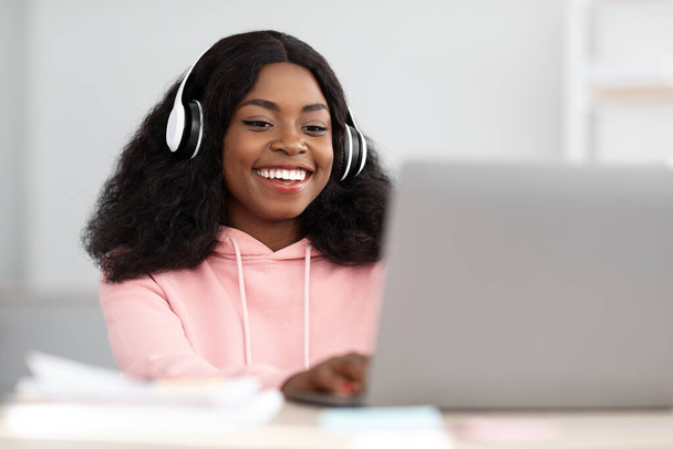 Pozitivní černošky žena navštěvující vzdělávací webinář, pomocí notebooku a sluchátek - Fotografie, Obrázek