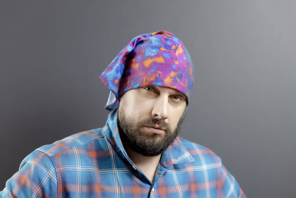 Porträt eines Mannes mit Bart, hellem Kopftuch und kariertem Hemd mit Blick - Foto, Bild