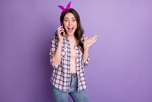 Photo portrait of cheerful surprised woman talking on mobile phone staring isolated on bright purple color background - 写真・画像