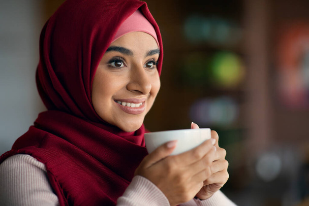 Closeup portrait of beautiful muslim woman drinking coffee at cafe - Foto, Bild