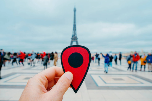 ruka mladého bělocha s červenou značkou ukazující na Eiffelovu věž v Paříži ve Francii - Fotografie, Obrázek