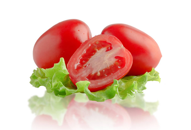 Dvě rajčata a půl na listě salátu. Izolováno na bílém pozadí. - Fotografie, Obrázek