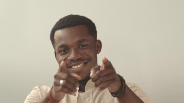 Schulterblick eines jungen, fröhlichen Afroamerikaners, der lächelnd mit den Fingern in die Kamera zeigt - Filmmaterial, Video