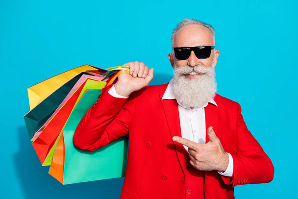 Photo portrait aged man in sunglass pointing finger bags after shopping isolated vibrant blue color background - Φωτογραφία, εικόνα