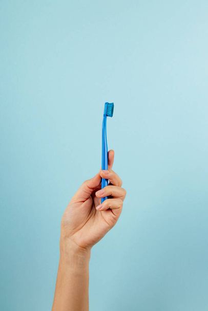 Compteur de dents bleu à la main féminine sur fond bleu clair - Photo, image