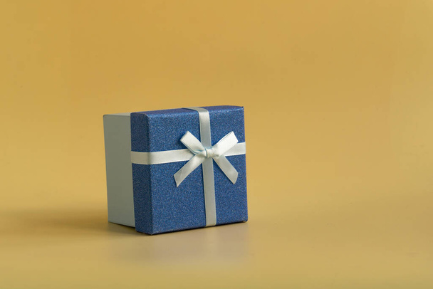 The gift is tied with a soft green ribbon on a yellow background - Fotó, kép