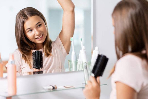 teenage girl singing to hairbrush at bathroom - Valokuva, kuva
