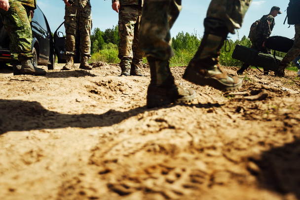 los pies de los soldados en botas del ejército están de pie sobre la arena. campo de entrenamiento antes de una larga marcha - Foto, imagen