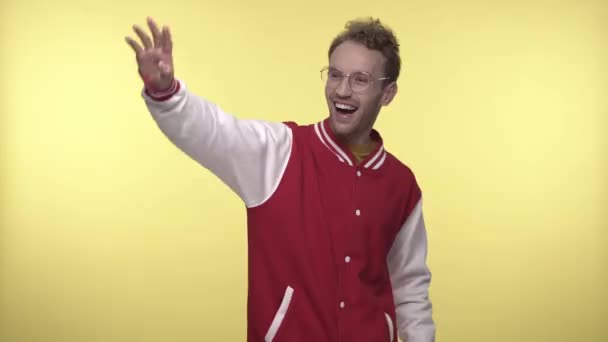 joyeux jeune homme dans des lunettes agitant la main et pointant avec les doigts sur jaune - Séquence, vidéo