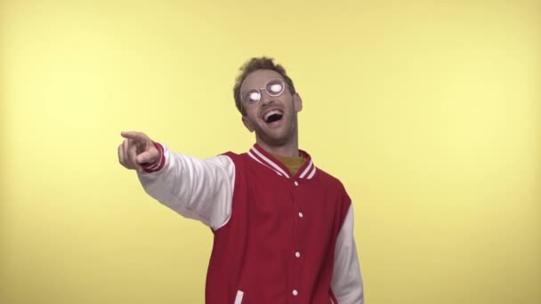 joyeux jeune homme dans des lunettes riant et pointant du doigt sur jaune - Séquence, vidéo