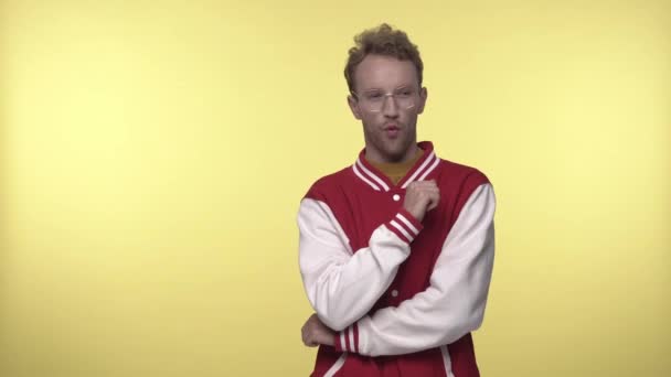 flirterige jongeman in bril het controleren van iemand op gele achtergrond - Video