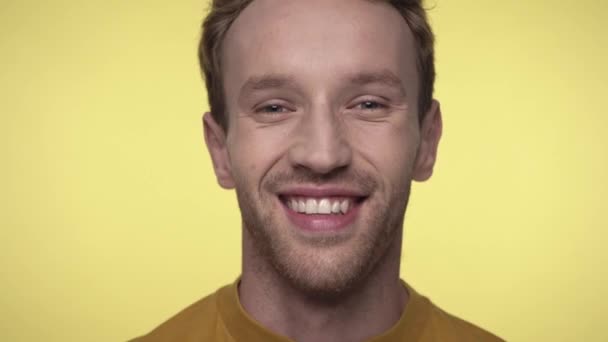 glücklicher Mann, der in die Kamera schaut, während er isoliert auf gelb lacht - Filmmaterial, Video