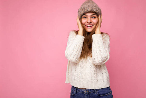 Attractive smiling happy young brunet woman standing isolated over colorful background wall wearing everyday stylish outfit showing facial emotions looking at camera - Foto, imagen