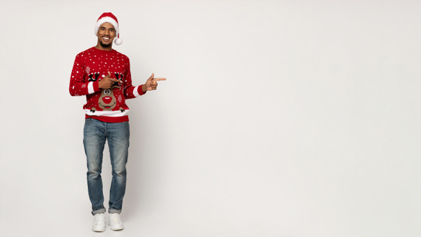 Noel Baba şapkalı pozitif siyah adam fotokopi alanını işaret ediyor. - Fotoğraf, Görsel