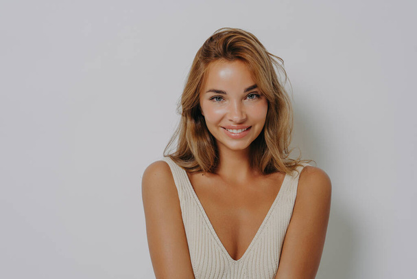 Jonge vrolijke blonde Europese vrouw met make-up glimlacht teder - Foto, afbeelding