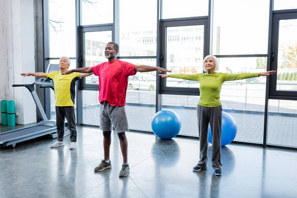 Personas mayores interraciales entrenando juntas en un centro deportivo  - Foto, imagen
