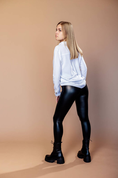 A beautiful woman in a white shirt and leather leggings and in stylish shoes. New collection of women's shoes with genuine leather - Foto, Imagem