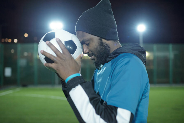Вид сбоку на молодого спортсмена с футбольным мячом на лбу - Фото, изображение