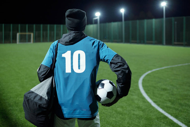 Parte posterior del jugador de fútbol con pelota y bolsa de fútbol que se mueve hacia el campo - Foto, imagen