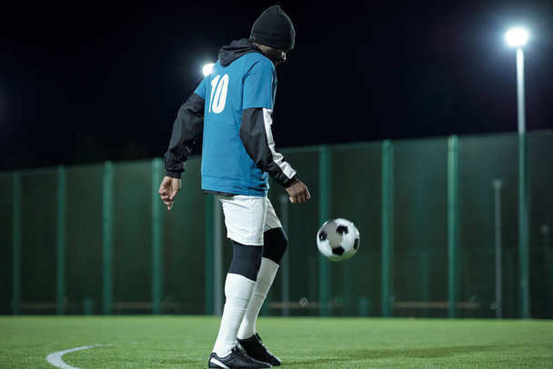 Junger Schwarzfahrer in Fußballprofi-Uniform spielt auf dem Feld - Foto, Bild