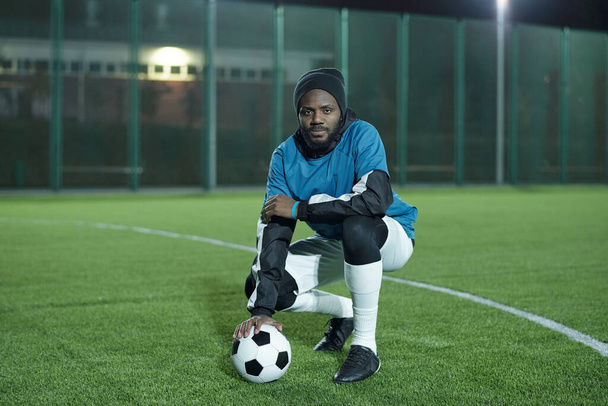 Nuori afrikkalainen jalkapalloilija jalkapallo istuu kyykky - Valokuva, kuva