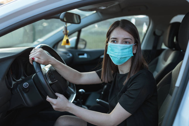 A Caucasian female in a face mask driving a car - Fotoğraf, Görsel
