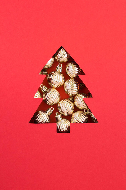 Árvore de Natal cortada no fundo vermelho e preenchida com bolas de ouro. Close-up. Localização vertical. - Foto, Imagem