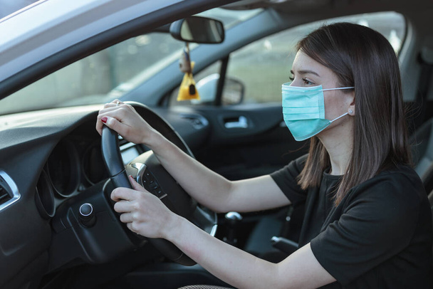 A Caucasian female in a face mask driving a car - Foto, afbeelding
