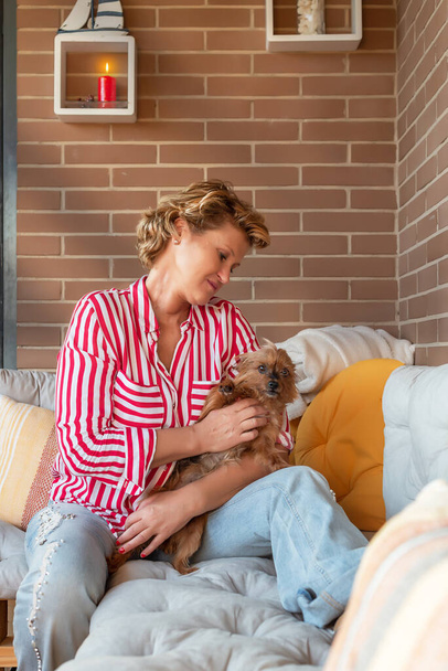 Middle-aged blonde woman with her yorkshire dog in her arms - Photo, Image