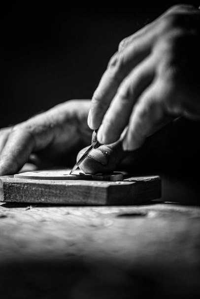 DILIJAN, ARMENIA - Nov 09, 2021: A grayscale shot of an old person carving a piece of wood in the workshop - Foto, Imagen
