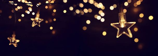 Christmas warm gold garland lights over dark background with glitter overlay - Fotó, kép
