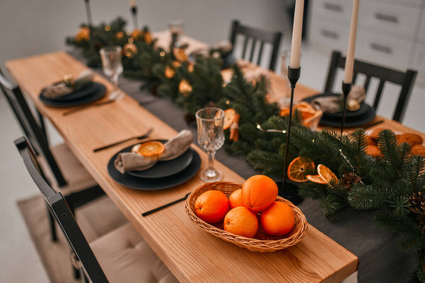 Wesołych Świąt i Szczęśliwego Nowego Roku! Przygotowuję świąteczną kolację. Nakrycia do stołu i dekoracje świecami, gałązkami świerku i suszonymi klinami pomarańczowymi. - Zdjęcie, obraz